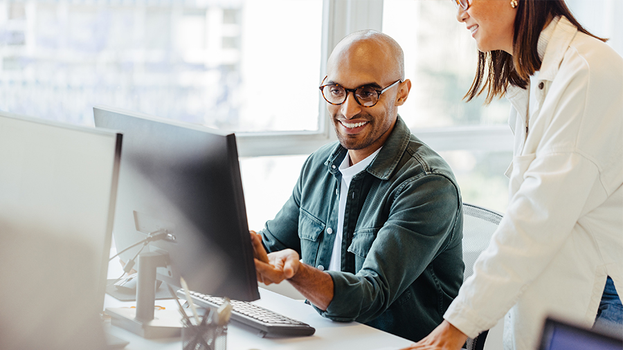 Software engineers using a computer and having a discussion in an office